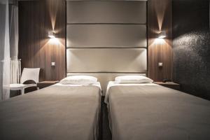 a bedroom with two beds and a headboard and lights at Hotel Schtak in Cannes