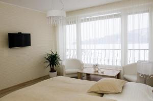 a bedroom with a bed and two chairs and a tv at Penzion Jollien in Námestovo