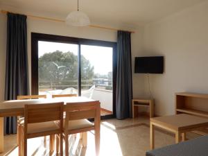 - un salon avec une table à manger et une grande fenêtre dans l'établissement Marina Palmanova Apartamentos, à Palma Nova