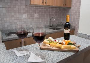 two glasses of wine and a cutting board with food and vegetables at Hotel Plaza Ñuñoa in Santiago