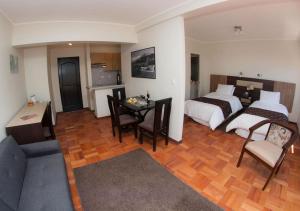 サンティアゴにあるHotel Plaza Ñuñoaのベッド2台、テーブル、ソファが備わるホテルルームです。