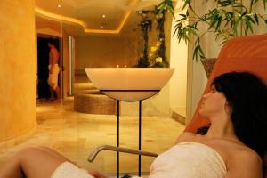a woman sitting in a chair next to a bath tub at Alpin Hotel Sonnblick in Perca