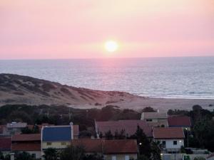 um pôr-do-sol sobre uma praia com casas e o oceano em Ramat Poleg, walk to beach em Netanya
