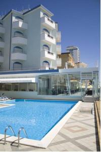 a swimming pool in front of a large building at Aparthotel Royal in Lido di Jesolo
