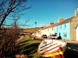 a boat sitting on the grass in front of houses at Sea Song, Selkie House in Helmsdale