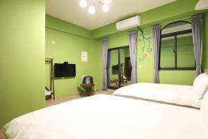 a green bedroom with a bed and a tv at 蘑菇城堡民宿 in Taitung City