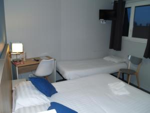 アブヴィルにあるLe Relais Vaubanのベッド2台、デスク、デスクが備わる客室です。