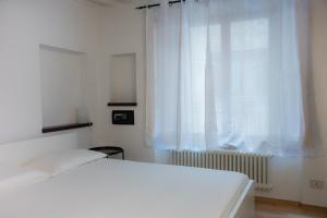 Un dormitorio blanco con una cama y una ventana. en La casa in Camollia, en Siena
