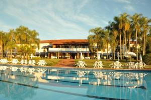 a swimming pool with white chairs and a building at Hotel Península in Avaré