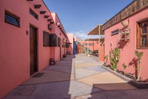 un callejón entre dos edificios rosas con plantas en Hostal Montepardo en San Pedro de Atacama