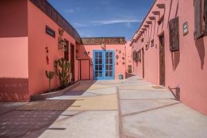 een steegje met een blauwe deur in een roze gebouw bij Hostal Montepardo in San Pedro de Atacama