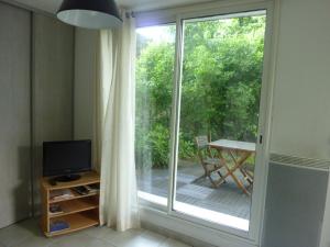 sala de estar con puerta corredera de cristal y TV en Gîte du Tilleul, en Vienne
