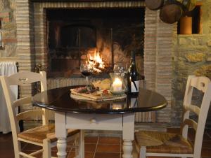 a table with a pizza and a bottle of wine and a fireplace at Il Poggiolo di Parrano in Parrano