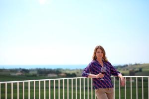 a woman is standing next to a fence at La Foresteria Planeta Wine Resort & Beach Club in Menfi