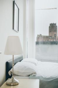 uma cama com um candeeiro numa mesa ao lado de uma janela em Serviced Apartment In Liverpool City Centre - Free Parking - Balcony - by Happy Days em Liverpool