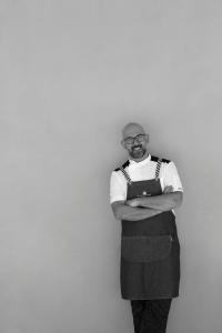 a man wearing glasses and apron holding a folder at La Foresteria Planeta Wine Resort & Beach Club in Menfi