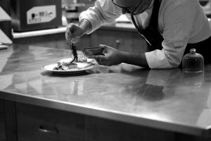 a chef preparing a plate of food on a counter at La Foresteria Planeta Wine Resort & Beach Club in Menfi
