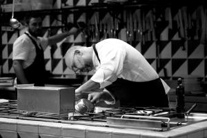 un hombre de pie en una cocina preparando comida en La Foresteria Planetaestate, en Menfi