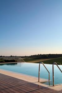 a swimming pool with blue water and metal rails at La Foresteria Planeta Wine Resort & Beach Club in Menfi