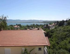 a house with a red roof with a lake in the background at Guest Home Elena in Star Dojran
