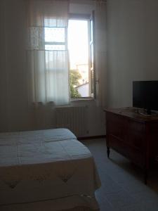 - une chambre avec un lit, une télévision et une fenêtre dans l'établissement RESIDENZA LEON D'ORO, à Cesena