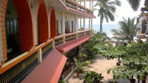 a building on the beach with the ocean in the background at Beach Florra Inn in Kovalam