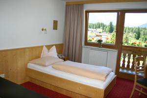 a bedroom with a bed and a large window at Hotel Hochland in Leutasch