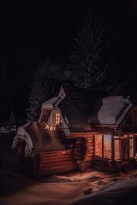 uma cabana com neve à noite em Lodge Nadgora em Žabljak