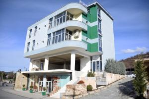 a large white building with a green at Hotel Latifi in Gramsh