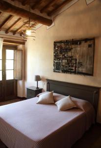 um quarto com uma cama branca e uma pintura na parede em La Tana del Bianconiglio em Castiglione dʼOrcia