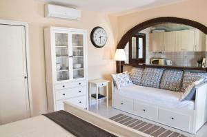 ベナルマデナにあるCasa Christabel y Casa Annabelのソファ付きのベッドルーム1室、壁に時計が備わります。