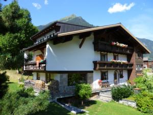 une maison dans les montagnes avec des montagnes en arrière-plan dans l'établissement Apartments Suggadin, à Sankt Gallenkirch