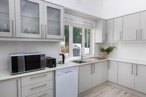 a white kitchen with a microwave and a sink at Villa on Camps Bay Drive in Cape Town