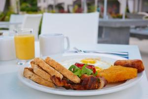 a plate of breakfast food with bacon and eggs and a glass of orange juice at Beach View Hotel in Saint James