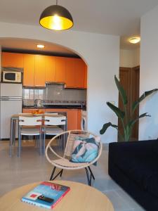 ein Wohnzimmer mit einem Tisch und eine Küche mit orangefarbenen Schränken in der Unterkunft Los Boliches wifi 300 m playa beach in Fuengirola