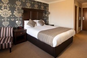 a bedroom with a large bed and a chair at Wessex Hotel in Street