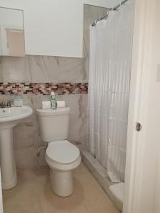 a white bathroom with a toilet and a sink at Golden Palms House in Nassau