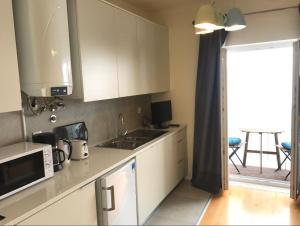 uma cozinha com armários brancos, um lavatório e um micro-ondas em Central Madragoa Flat em Lisboa