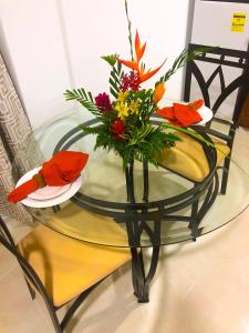 a glass table with a vase of flowers on it at Calliandras Apartment Complex in Kingstown