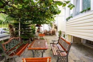 a patio with two benches and a table and a table and chairs at Guest House Gardeli in Tsarevo