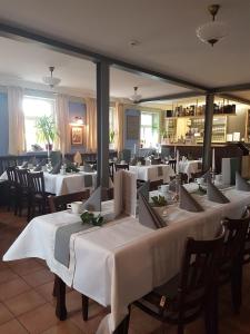 een restaurant met tafels en stoelen met witte tafelkleden bij Wirtshaus am Markt in Markt Nordheim