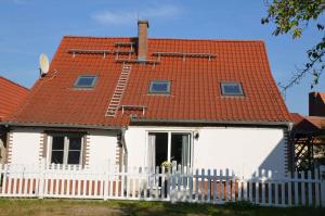 Casa blanca con techo rojo y valla blanca en Ferienhaus Spreewiese, en Schlepzig