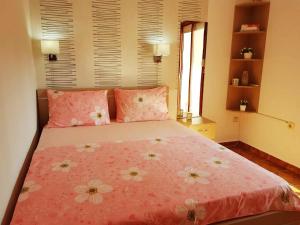 Un dormitorio con una cama rosa con flores. en Apartments Taida en Dobra Voda
