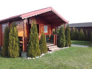 Cette cabane en rondins dispose d'une terrasse couverte et d'une table. dans l'établissement Domki Letniskowe ,,Tęcza", à Rusinowo