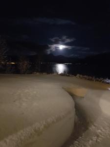 une pleine lune sur une masse d'eau la nuit dans l'établissement Solbakken 27 Apartment, à Lyngseidet