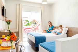 two girls sitting on a bed in a hotel room at Pousada Madre Guarda in Guarda do Embaú