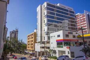 un alto edificio bianco su una strada di città con le auto di Apartamento com Piscina no Centro e a poucos metros do mar de Torres -RS a Torres