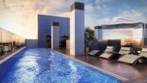 una piscina con sedie e un edificio di Apartamento com Piscina no Centro e a poucos metros do mar de Torres -RS a Torres