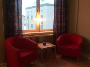 two red chairs and a table in front of a window at Grand Hotell in Strömsund