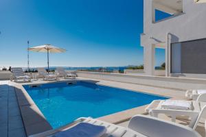 una piscina con sillas y sombrilla en Dario 2. modern & luxury apartment with a pool, en Novalja